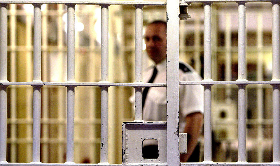 A prison guard at Her Majesty's Prison, Pentonville stands behind a locked gate May 19, 2003 in London.