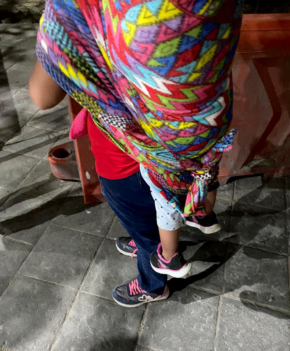 Image: A migrant woman waits with her child on her back (Taylor Levy)