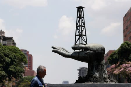 FILE PHOTO: A man walks past a sculpture outside a building of Venezuela's state oil company PDVSA in Caracas