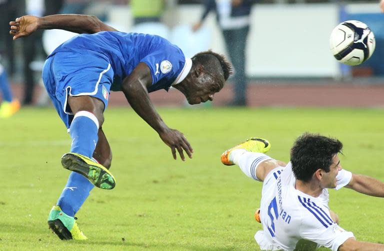 Italy forward Mario Balotelli (L) heads the ball as Armenia's Robert Arzumanyan falls during the 2014 World Cup Qualifier football match on October 15, 2013 at the San Paolo stadium in Naples