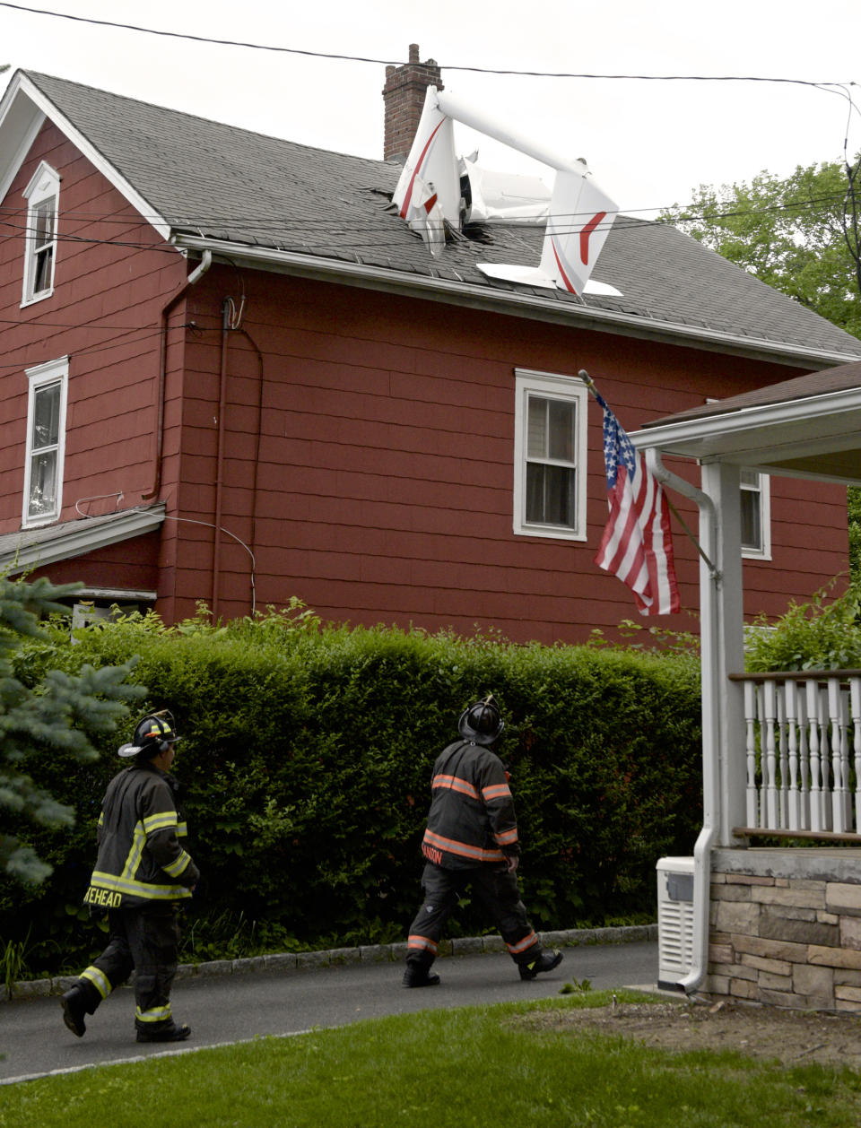 In this Tuesday evening, June 4, 2019 photo, a glider, flown by a local business owner, crashed into a house on Golden Hill Avenue while making its approach to Danbury Airport, in Danbury, Conn. Officials say the pilot sustained minor injuries. (H John Voorhees III/Hearst Connecticut Media via AP)
