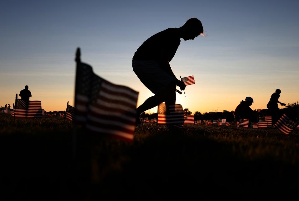 Volunteers with the COVID Memorial Project install 20,000 American flags on the National Mall as the United States crosses the 200,000 lives lost in the COVID-19 pandemic September 20, 2020 in Washington, DC. The flags are displayed on the grounds of the Washington Monument facing the White House.