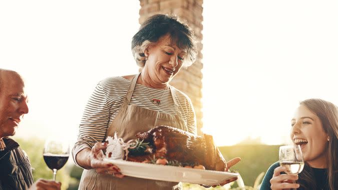 Shot of a senior woman serving roasted chicken at a dinner party.