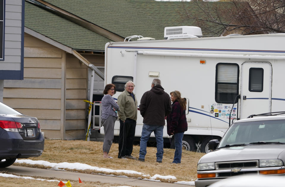 Neighbors gather on the lawn next to the home of Kirby Klements after a piece of debris crushed the man's pickup truck parked next to his home in Broomfield, Colo., as the plane shed parts while making an emergency landing at nearby Denver International Airport Saturday, Feb. 20, 2021. (AP Photo/David Zalubowski)