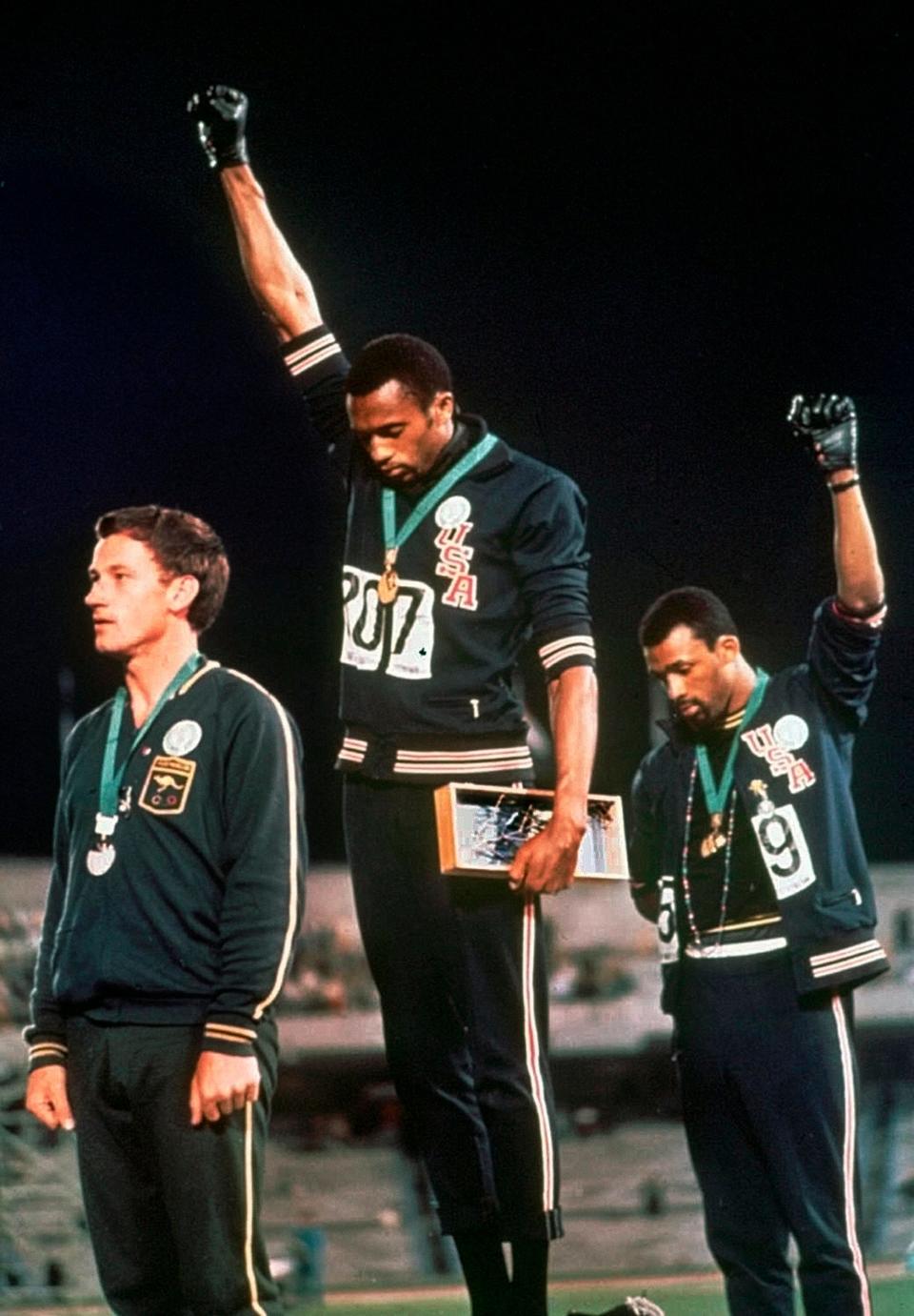 U.S. athletes Tommie Smith, center, and John Carlos extend gloved hands skyward in racial protest during the playing of national anthem at the 1968 Olympics.