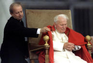 Pope John Paul II's personal secretary Stanislaw Dziwisz adjusts the Pontiff's cloak during his weekly general audience October 2, 1996. REUTERS/Paul Hanna/File Photo