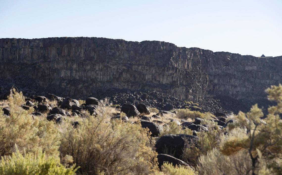 Sharp-edged basalt cliffs rise above rounded basalt boulders near the Snake River at Celebration Park.