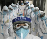 In this photo taken and released by Chinese nurse Zhang Dan, she poses for a photo with colleagues at the Wuhan Pulmonary Hospital in Wuhan in central China's Hubei province, Friday, April 4, 2020. Zhang was among the first to respond to the call for help in China's coronavirus epicenter. The 36-year-old nurse worked through grueling days, ministering to patients who needed assistance from breathing to merely eating. She struggled — but then, a little street dog helped her through. (Zhang Dan via AP)