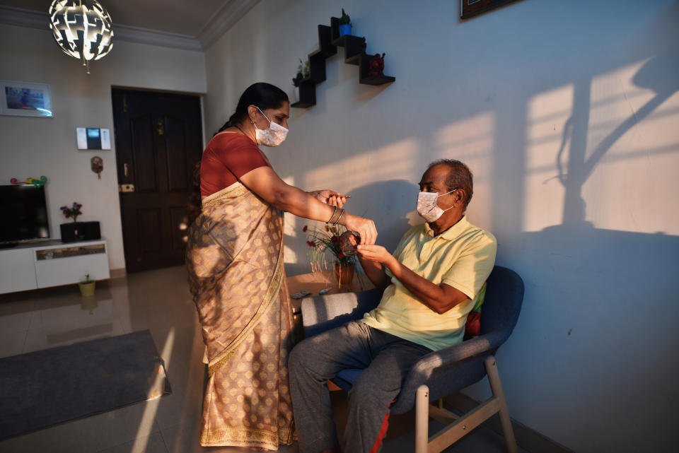 Senior woman wearing medical mask giving medicine to husband