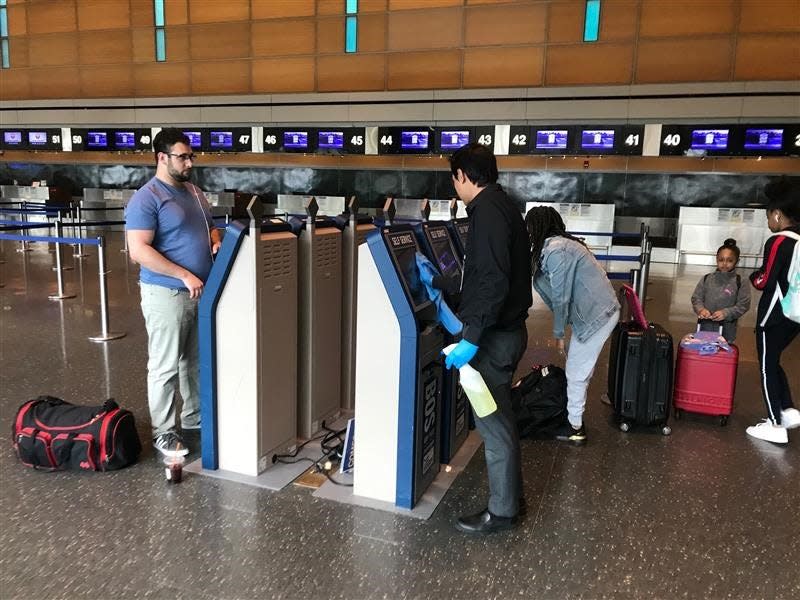 A worker cleans the surface of a baggage check-in kiosk at Boston Logan International Airport on Thursday, March 12, 2020. Few passengers could be found in the terminal because of the warnings and cancellations due to the coronavirus, now a global pandemic.