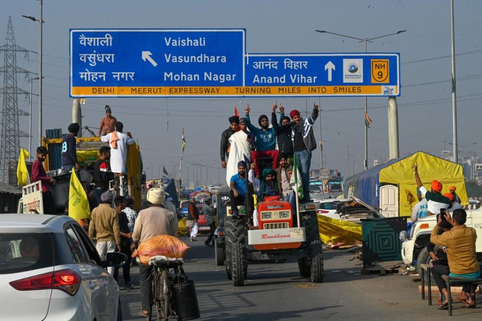 Farmers ride on a tractor as they leave the protest site at the Delhi-Uttar Pradesh state border in Ghazipur on 11 December 2021 (AFP/Getty)