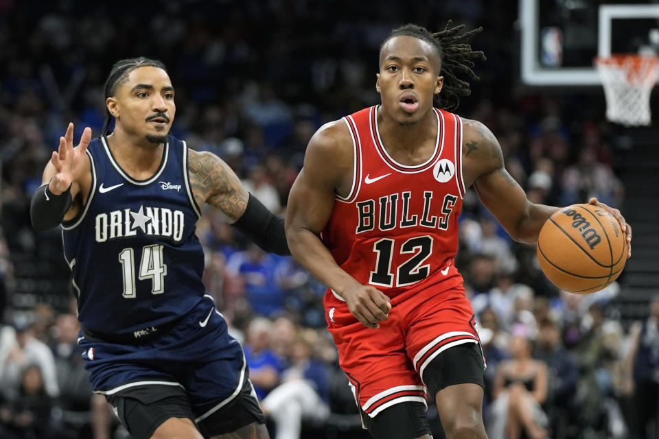 Chicago Bulls guard Ayo Dosunmu (12) drives past Orlando Magic guard Gary Harris (14) during the second half of an NBA basketball game, Sunday, April 7, 2024, in Orlando, Fla. (AP Photo/John Raoux)