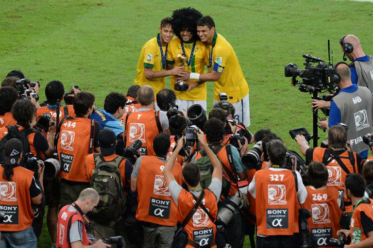 Brazil's Neymar (L), Dani Alves (C, wearing the jersey of teammate Damiao who had the leave the team due to an injury) and Thiago Silva pose with the FIFA Confederations Cup trophy, at the Maracana Stadium in Rio de Janeiro, on June 30, 2013