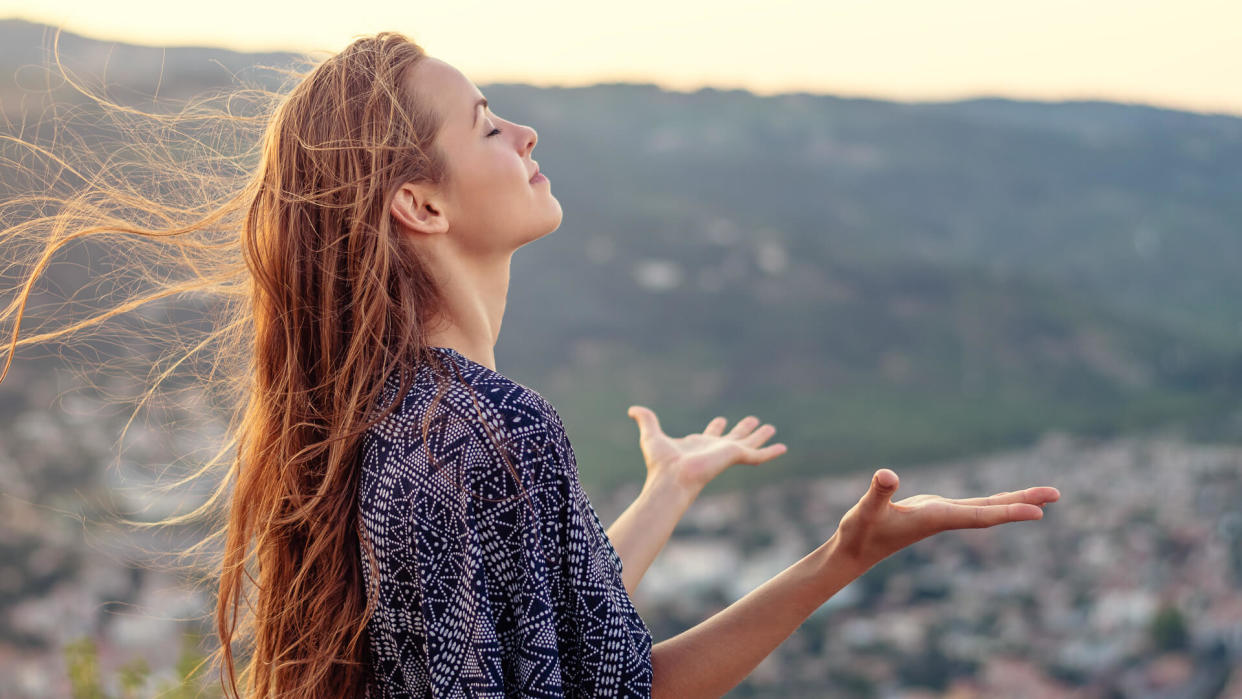 A young woman with her hands raised in worship and praise to god.