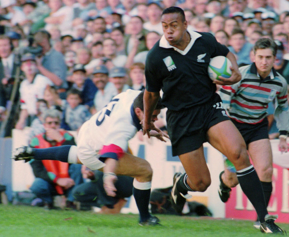 FILE - In this June 18, 1995 file photo, New Zealand All Blacks winger Jonah Lomu runs around England's Will Carling on his way to score the opening try in the Rugby World Cup semifinal at Newlands in Cape Town, South Africa. One trampling run launched Jonah Lomu to global stardom and ensured his name will be indelibly linked to a Rugby World Cup semifinal between New Zealand and England. The All Blacks winger’s rampaging runs during that era-defining World Cup in South Africa in 1995 were highlighted by his four-try haul against England in the semifinals. New Zealand and England meet again in the semifinals this Saturday, Oct. 26, 2019, at Yokohama. (AP Photo/Ross Setford, File)