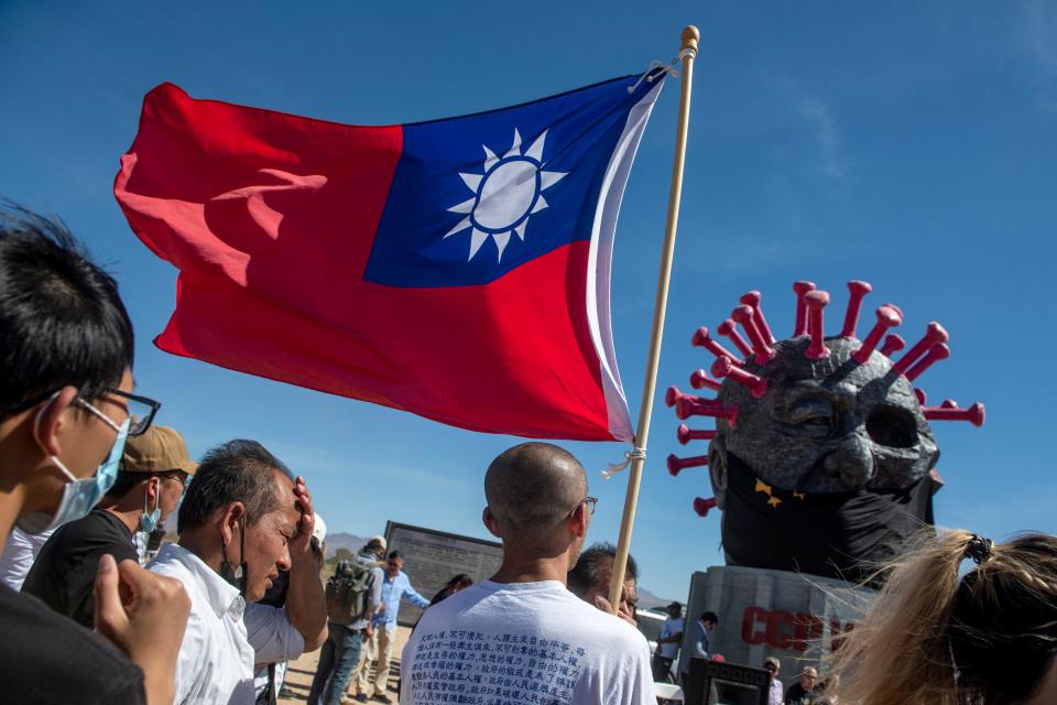 Visitors wave a Taiwan flag as Weiming Chen unveiled the new CCP Virus II sculpture at his Liberty Sculpture Park in Yermo on June 5, 2022. His original anti-COVID-19 and anti-communist sculpture was burned after it was unveiled.