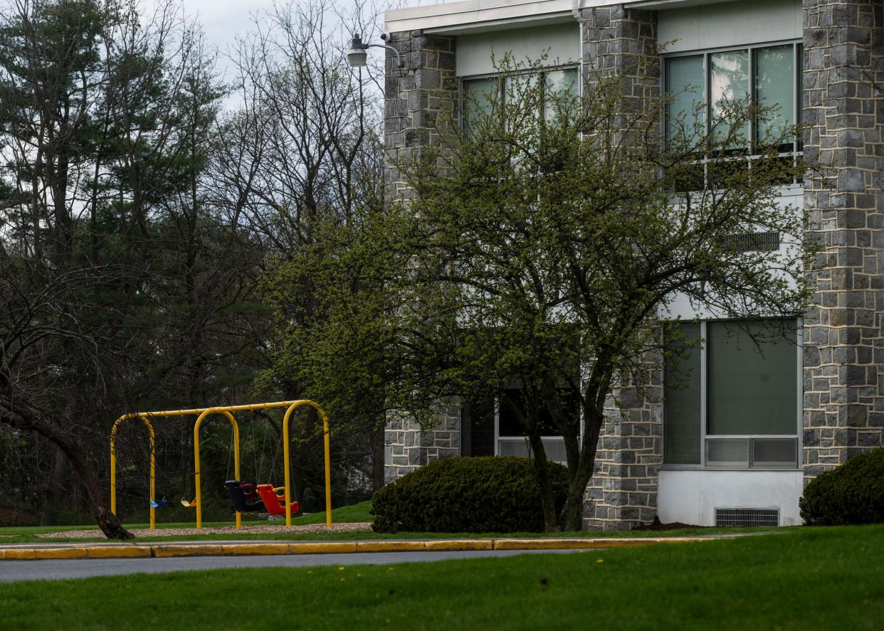 Empty swingset next to school building.