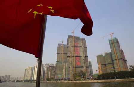 A Chinese national flag flutters on the Pearl River near a construction site in Guangzhou, Guangdong province, in this March 27, 2014 file photo. REUTERS/Alex Lee/Files