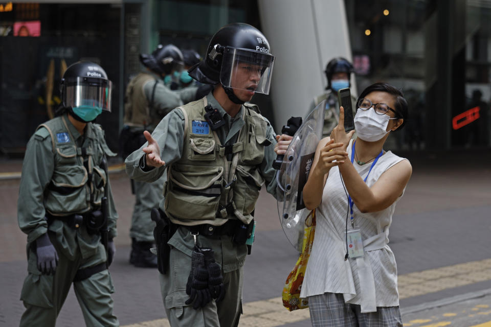Riot policeman pushes a woman as she is taking a photograph of the detained protesters at the area in Mongkok, Hong Kong, Wednesday, May 27, 2020. U.S. Secretary of State of Mike Pompeo has notified Congress that the Trump administration no longer regards Hong Kong as autonomous from mainland China. (AP Photo/Kin Cheung)
