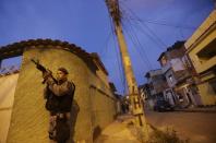 A police officer takes up position at the Vila Kennedy slum during an operation to install the Police Peacekeeping Unit (UPP) in the region in Rio de Janeiro March 13, 2014. The introduction of the peacekeeping program in the region is part of efforts to crack down on crime and increase security as the city prepares to host the 2014 World Cup soccer tournament and the 2016 Olympic Games. REUTERS/Ricardo Moraes (BRAZIL - Tags: CRIME LAW CIVIL UNREST TPX IMAGES OF THE DAY)