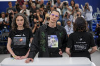 Producers Darya Bassel, left, and Yelizaveta Smith, right, wearing t-shirts that have an image of an explosion on the front and read "Sensitive Content: Russians kill Ukrainians. Do you find it offensive and disturbing to talk about this genocide?" pose with director Maksym Nakonechnyi who wears a t-shirt that reads "Free Tayra" in reference to Julia Paevska, aka Tayra, a Ukrainian medic who Russian forces have taken captive at the photo call for the film 'Butterfly Vision' at the 75th international film festival, Cannes, southern France, Wednesday, May 25, 2022. (AP Photo/Daniel Cole)