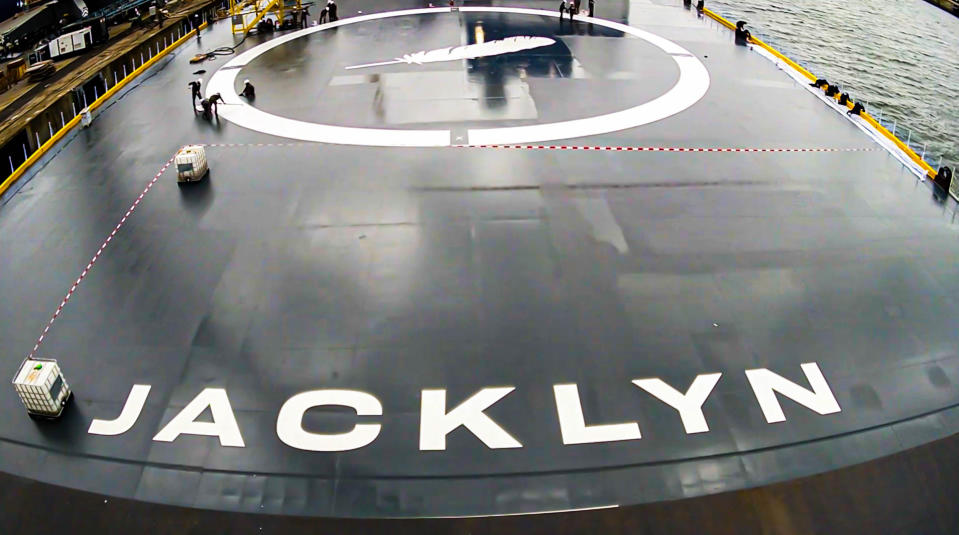 closeup of a ship's deck, which has a large white painting of a feather and the name 