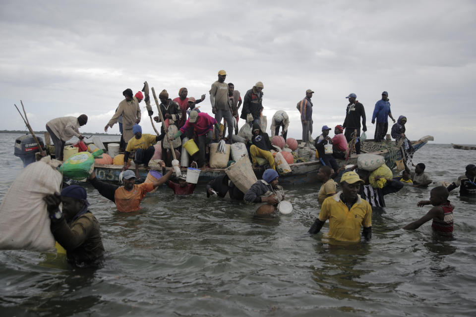 Fishermen swim out from an incoming boat at a berth, some with their overnight catch in Kwale county, Gazi Bay, Kenya on Sunday, June 12, 2022. Artisanal fisheries on Kenya's coast say climate change, overfishing by large foreign vessels and a lack of other job opportunities for coastal communities is draining the Indian Ocean of its yellowfin tuna stocks. (AP Photo/Brian Inganga)