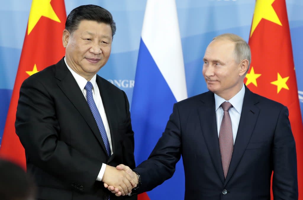 File: Russia’s President Vladimir Putin (R) shakes hands with his China’s counterpart Xi Jinping (AFP via Getty Images)