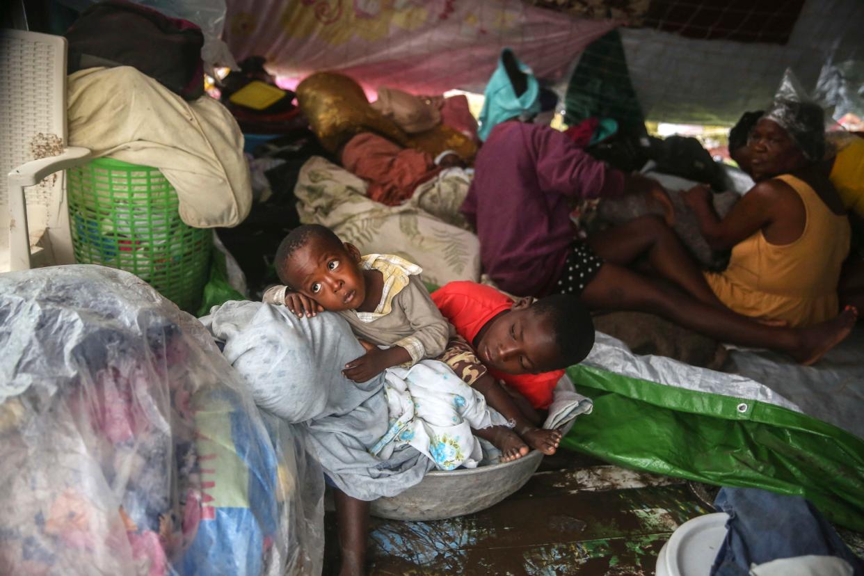 Earthquake-displaced people sit under blankets to shield themselves from the rain, the morning after Tropical Storm Grace swept over Les Cayes, Haiti, early Tuesday, Aug. 17, 2021, three days after a 7.2-magnitude earthquake.