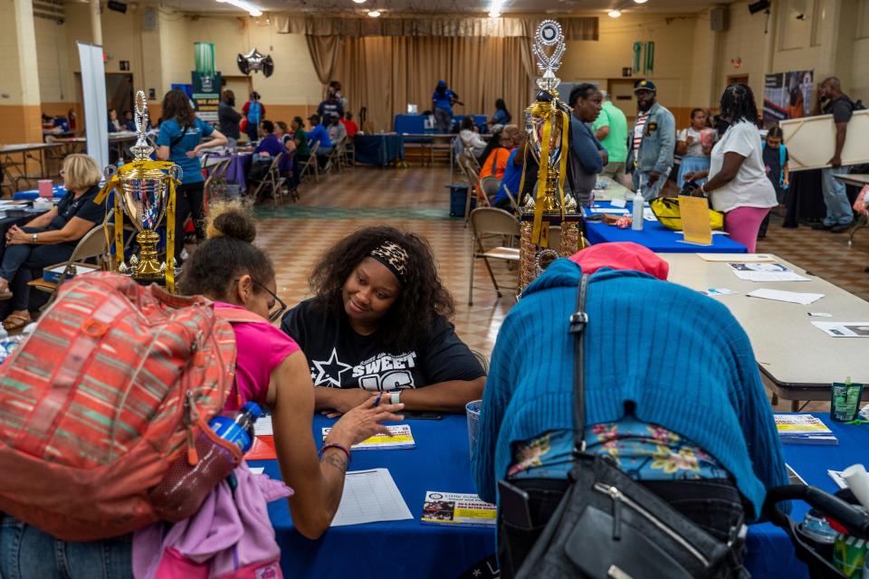 Jeanette Beckley, center, answers questions while sitting at a table recruiting students for Little Scholars Child Development Center during the Community Resource Fair at Christ the King Catholic School in Detroit on Aug. 18, 2023.