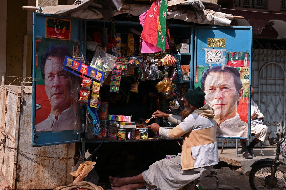 A vendor sits at his tuck shop displaying posters of Pakistan’s former prime minister and Pakistan Tehreek-e-Insaf (PTI) leader Imran Khan (AFP via Getty Images)
