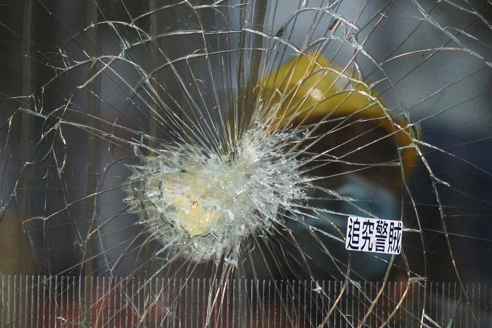 A worker is reflected on a broken glass panel damaged by protesters at the Legislative Council building in Hong Kong, Wednesday, July 3, 2019. A pro-democracy lawmaker who tried to stop Hong Kong protesters from breaking into the legislature this week says China will likely use the vandalizing of the building as a reason to step up pressure on the Chinese territory. (AP Photo/Andy Wong)