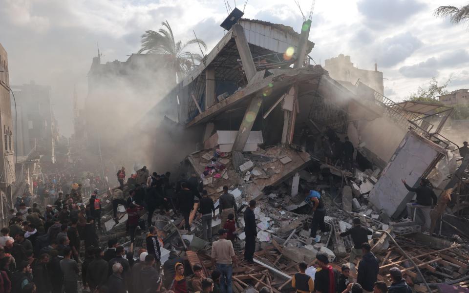 Rescuers and civilians look for survivors amid the rubble of destroyed buildings following Israeli bombardment in Rafah, in the southern Gaza Strip