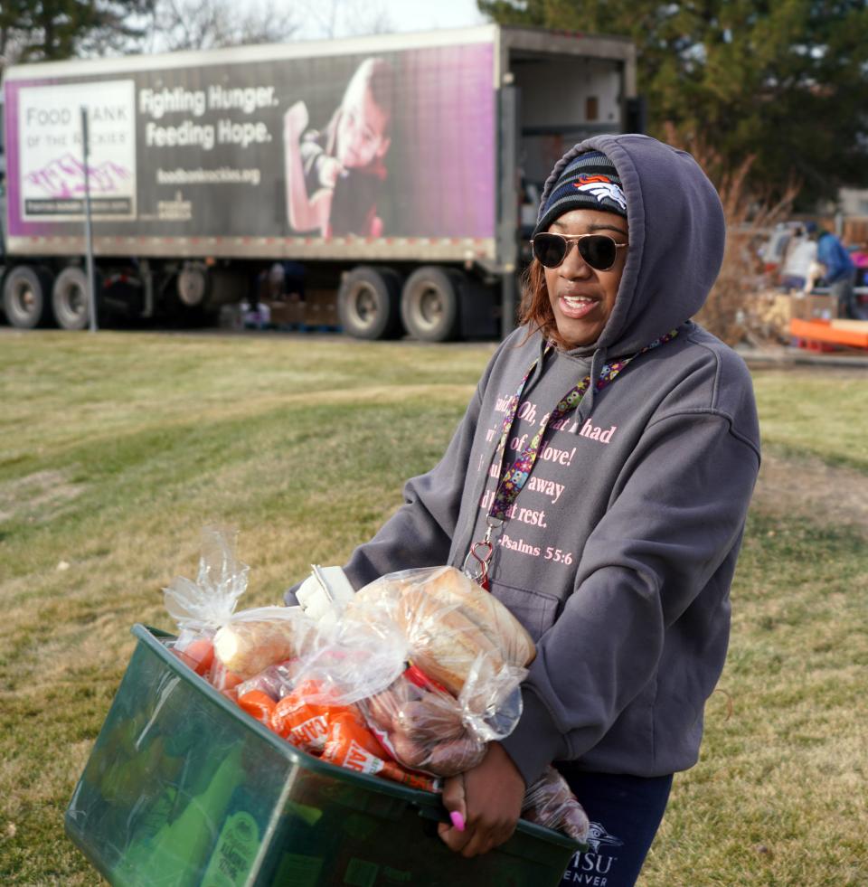 Iyonna Logan of Denver carries a box of food to her car after visiting a Food Bank of the Rockies distribution on Dec. 19, 2019.