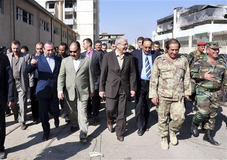 Syrian local officials pay a visit to Sbeineh town, in southern Damascus after soldiers loyal to Syria's President Bashar al-Assad, took control of it from rebel fighters last week, in this handout photograph distributed by Syria's national news agency SANA on November 15, 2013. REUTERS/SANA/Handout via Reuters