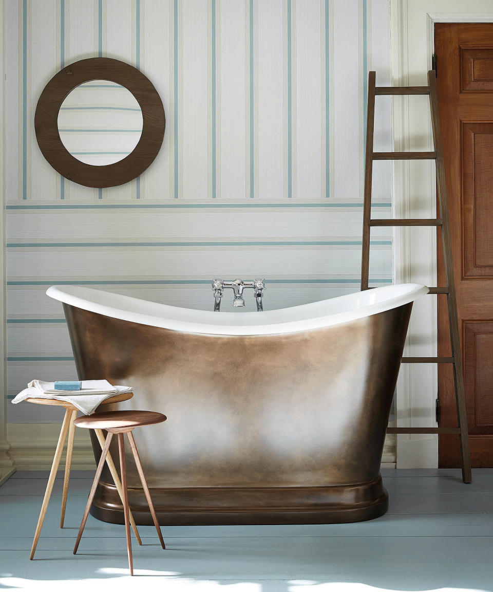 rolltop bath with striped wallpaper in front