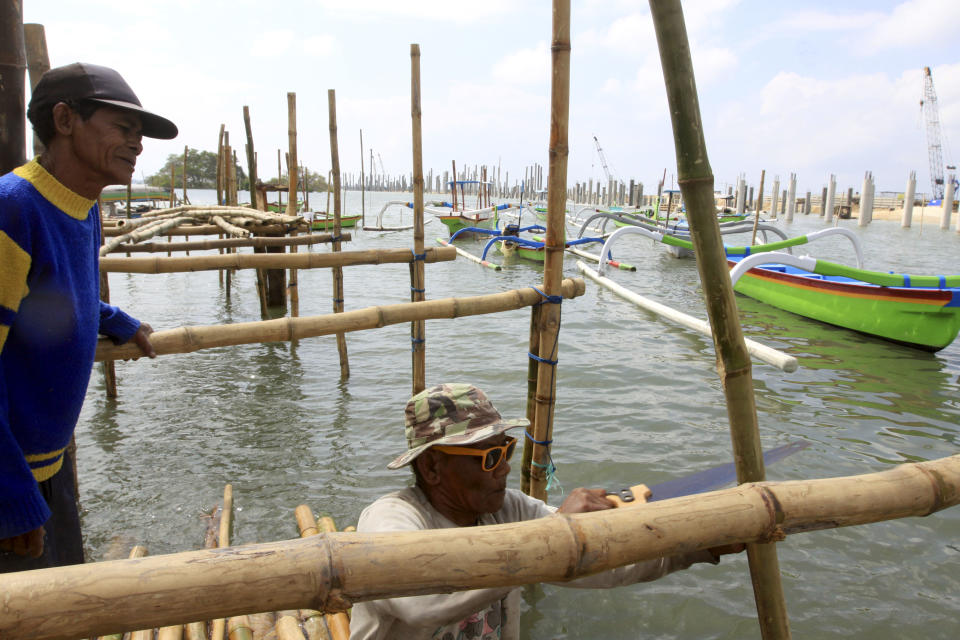 This Aug. 25, 2012 photo shows Balinese men building a bamboo bridge next to a road construction site in Kuta, Bali, Indonesia. It can be hard to find Bali's serenity and beauty amid the villas with infinity pools and ads for Italian restaurants. But the rapidly developing island's simple pleasures still exist, in deserted beaches, simple meals of fried rice and coconut juice, and scenes of rural life. (AP Photo/Firdia Lisnawati)