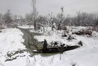 Kashmiri men try to push their boat through the waters of Anchar Lake after heavy snowfall in Srinagar January 1, 2014. The Srinagar-Jammu highway, Kashmir valley's link with the country, has been closed on Tuesday following heavy snowfall, local media reported. REUTERS/Danish Ismail (INDIAN-ADMINISTERED KASHMIR - Tags: ENVIRONMENT)