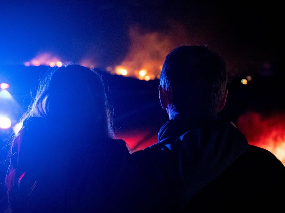 A wife and husband watch wildfires spread across the Colorado skyline.