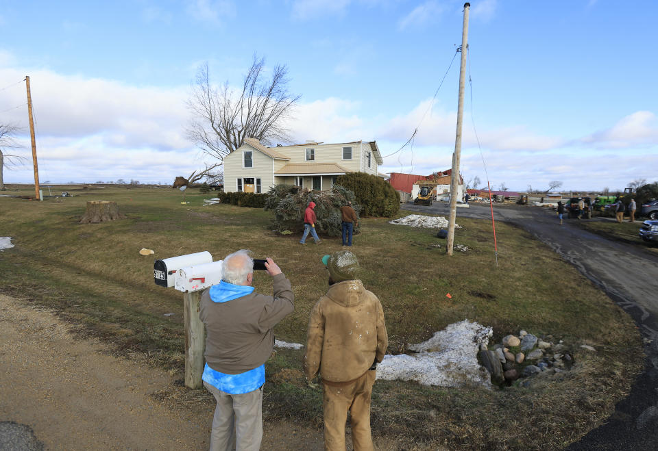Passersby capture photos of a home and barn which was damaged in a previous day's tornado in Porter, Wis., Friday, Feb. 9, 2024. The first tornado ever recorded in Wisconsin in the usually frigid month of February came on a day that broke records for warmth, the type of severe weather normally seen in the late spring and summer.(John Hart/Wisconsin State Journal via AP)