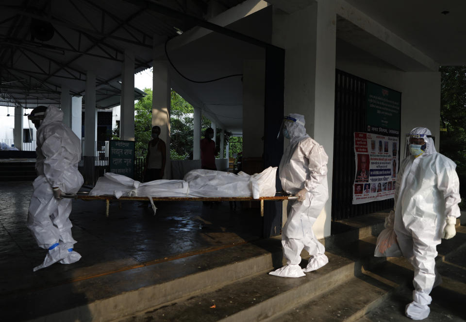 Health workers wearing personnel protection equipment carry the body of a COVID-19 victim for cremation in Lucknow, India, Saturday, Sept. 12, 2020. India's coronavirus cases are now the second-highest in the world and only behind the United States. (AP Photo/Rajesh Kumar Singh)