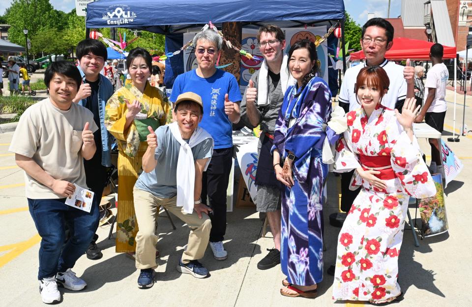 ASAMA president Kazumitsu Takeoka, in the white scarf and friends poised in front a Japanese booth during the Cultural Jubilee.