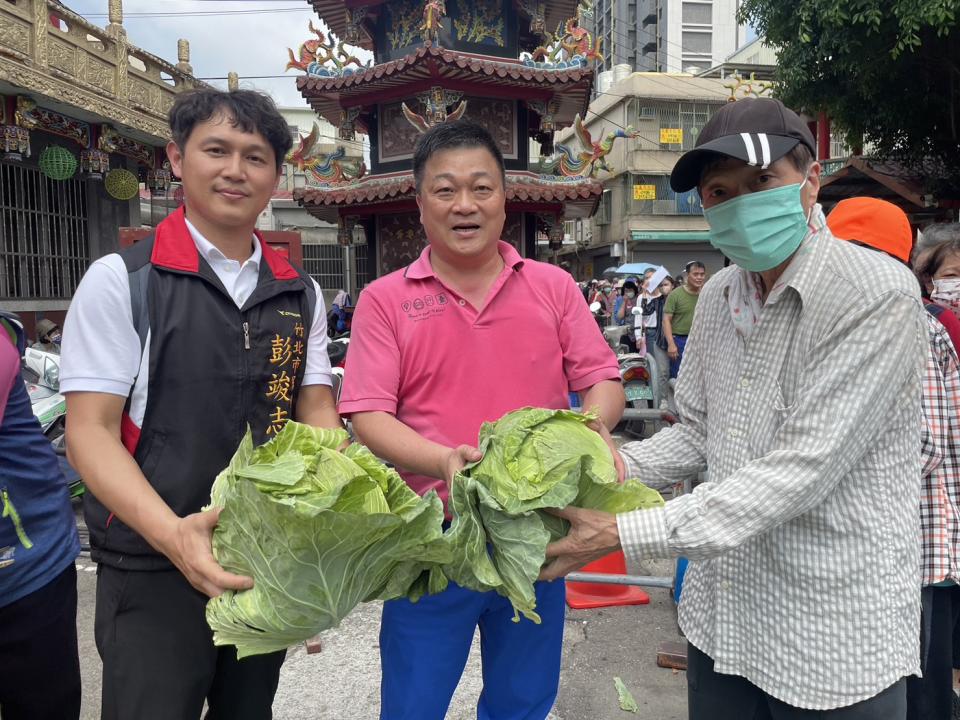 竹北天后宮主委、竹北市民代表主席林啟賢（中）及竹北市民代表彭竣志協助發送高麗菜予民眾，以解決目前高麗菜生產過剩的問題。（記者彭新茹攝）