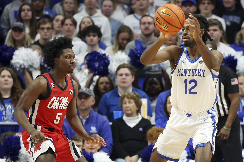 Kentucky's Antonio Reeves (12) passes the ball away from the defense of Mississippi's Jaylen Murray (5) during the second half of an NCAA college basketball game Tuesday, Feb. 13, 2024, in Lexington, Ky. Kentucky won 75-63. (AP Photo/James Crisp)