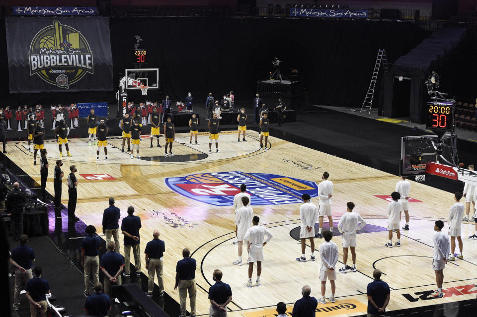 Virginia and Towson players stand for the national anthem before an NCAA college basketball game, Wednesday, Nov. 25, 2020, in Uncasville, Conn. (AP Photo/Jessica Hill)