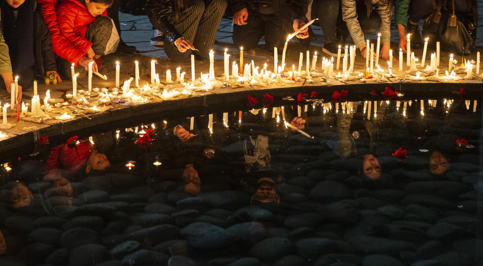 In this Sept. 11, 2019 photo, people light candles at the National Stadium during a vigil marking the anniversary of the 1973 military coup that ousted the late President Salvador Allende, in Santiago, Chile. The stadium was used as a detention center in the early years of the dictatorship. (AP Photo/Esteban Felix)