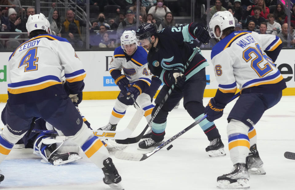 Seattle Kraken right wing Oliver Bjorkstrand (22) tries to work the puck to the net against St. Louis Blues defenseman Nick Leddy (4), defenseman Torey Krug (47) and left wing Nathan Walker (26) during the first period of an NHL hockey game Friday, Jan. 26, 2024, in Seattle. (AP Photo/Lindsey Wasson)