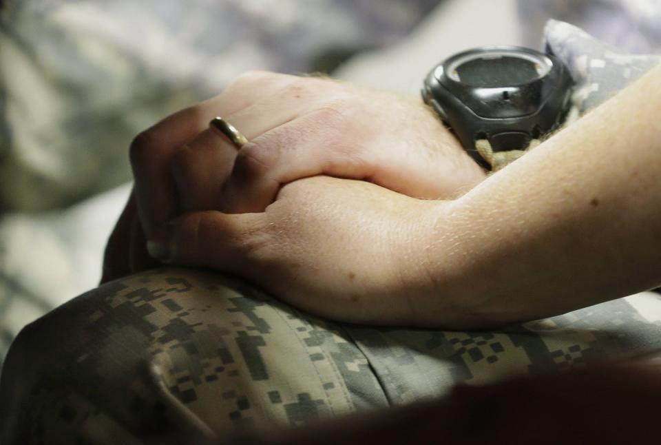 Close-up of two people holding hands, one of whom is wearing an army uniform