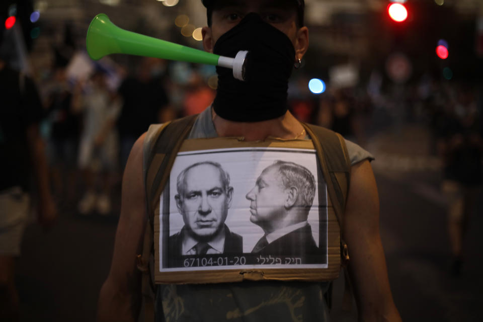 A protester wears a face mask to protect against the coronavirus during a protest against Israel's Prime Minister Benjamin Netanyahu in front of the Knesset, Israel's parliament in Jerusalem, Tuesday, July 21, 2020. (AP Photo/Ariel Schalit)