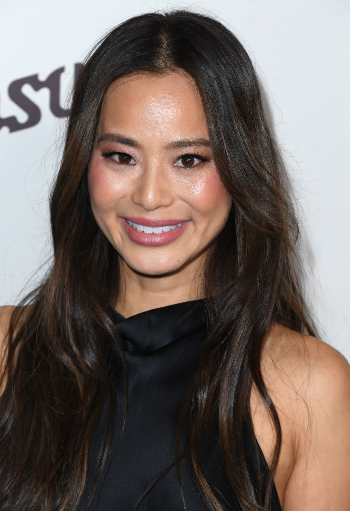 Jamie Chung smiles at a celebrity event, wearing a sleeveless black dress with her hair down